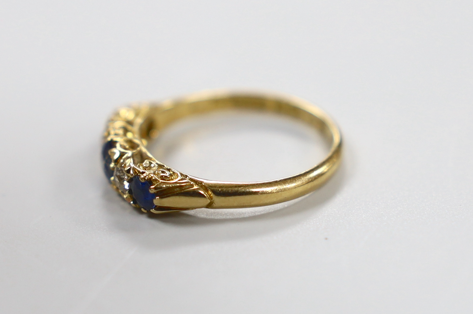 A late Victorian 18ct gold, three stone sapphire and two stone diamond set half hoop ring, size P, gross weight 3.8 grams.